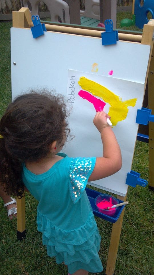 Child painting on an easel outdoors