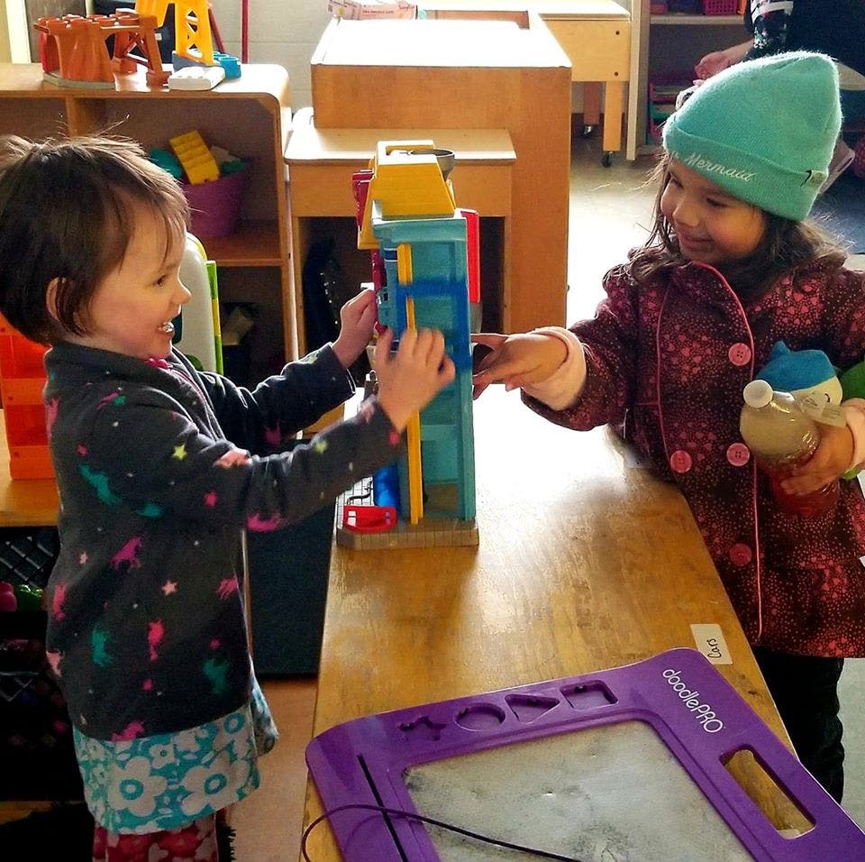 Two children playing with a toy on a table