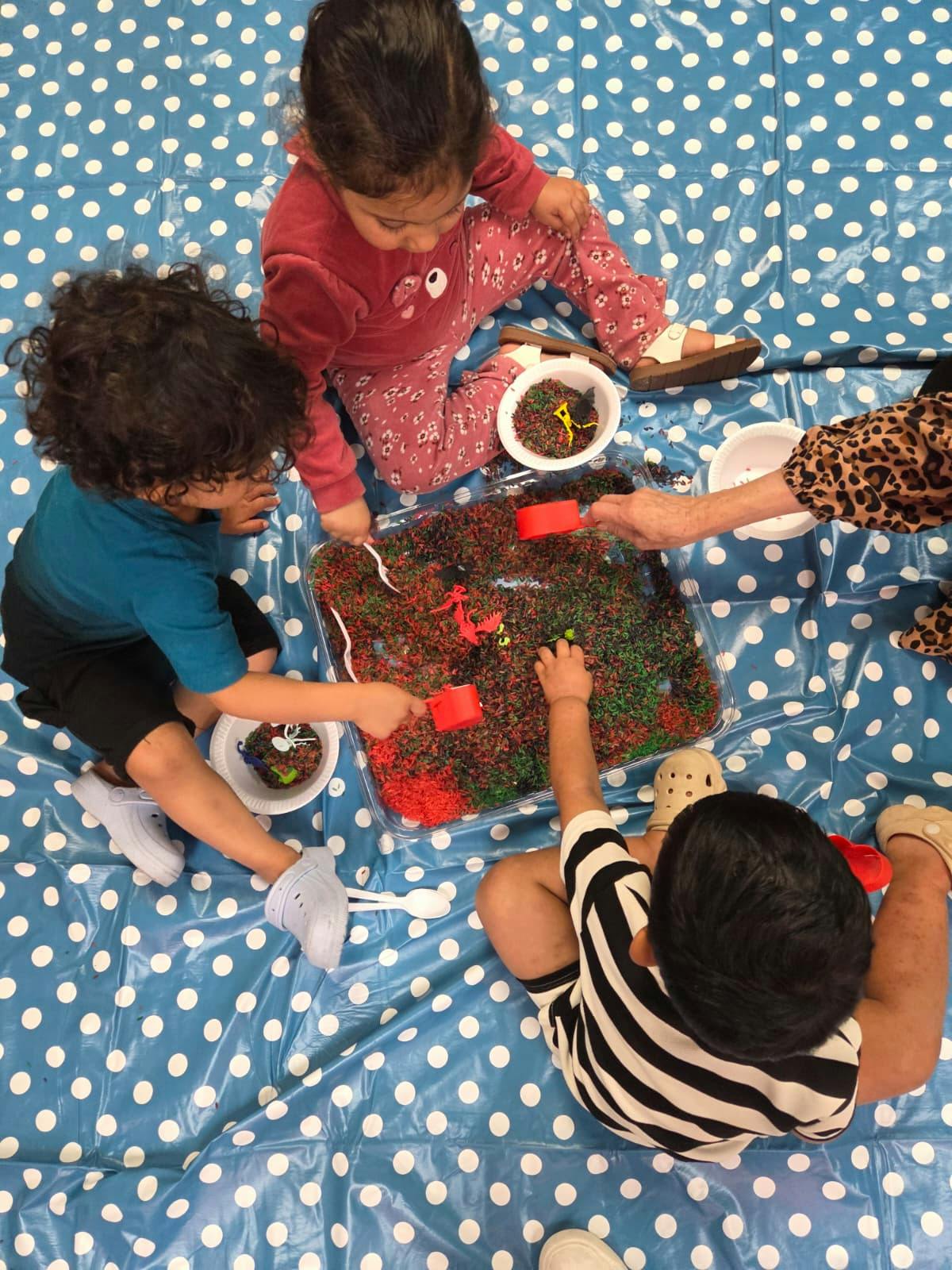 children playing with a tray of colorful rice and scoops