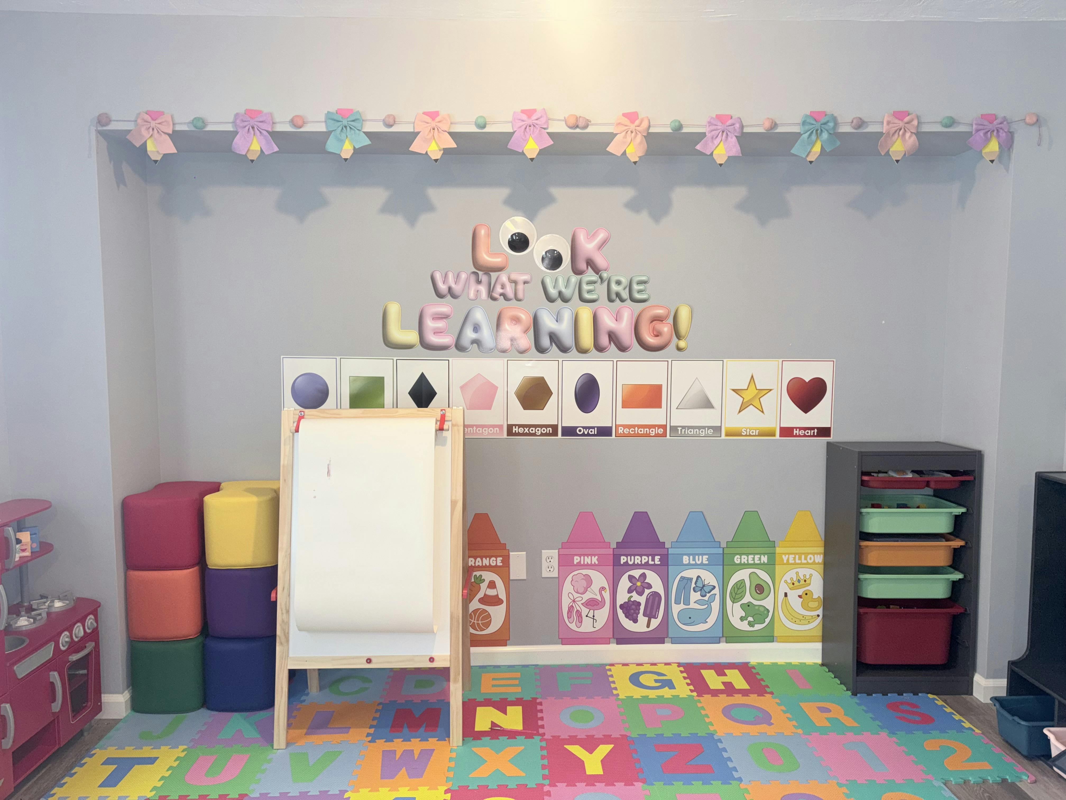 Playroom with educational wall decor, alphabet floor mats, and an art easel