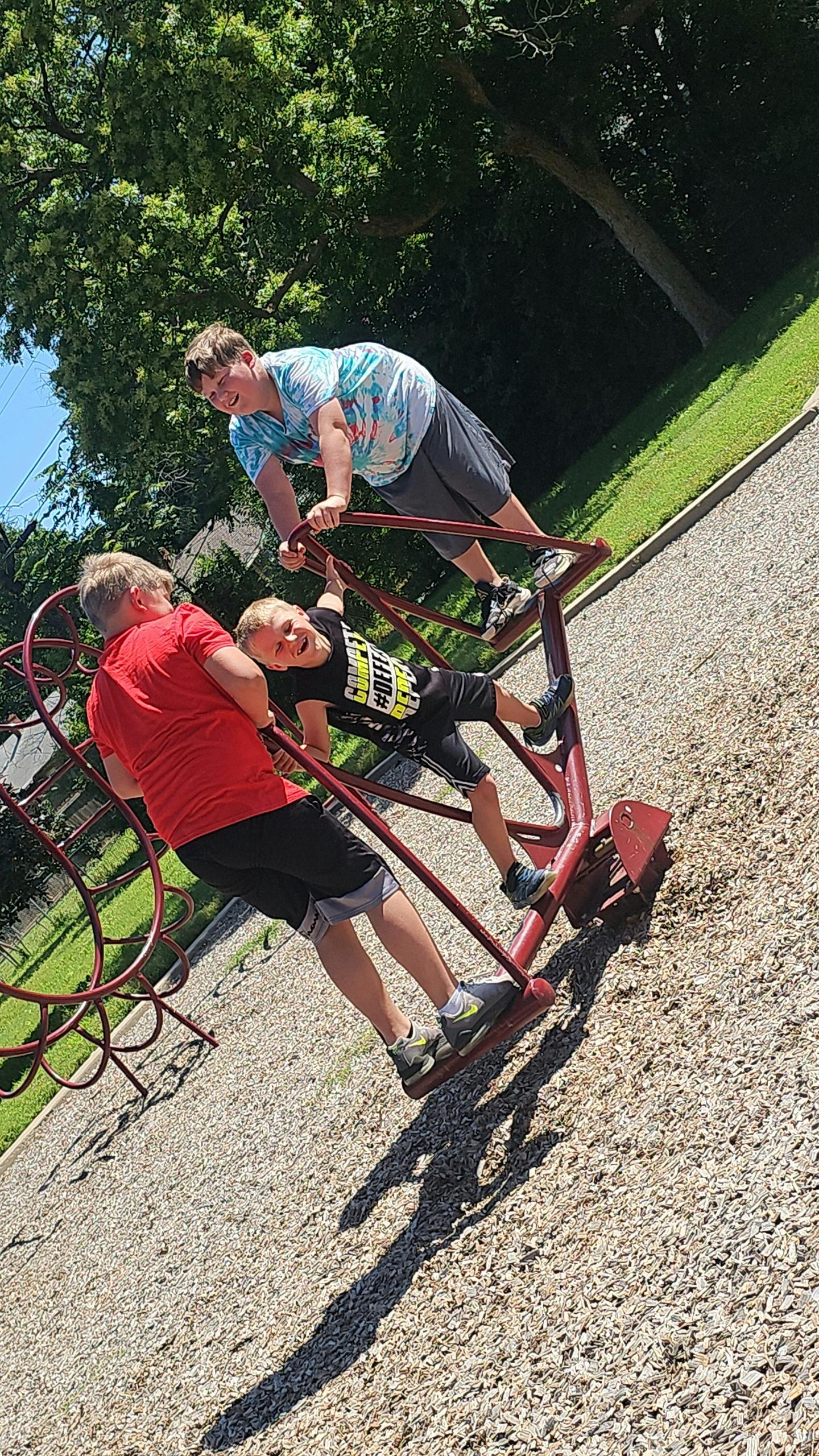 Three children playing on red playground equipment