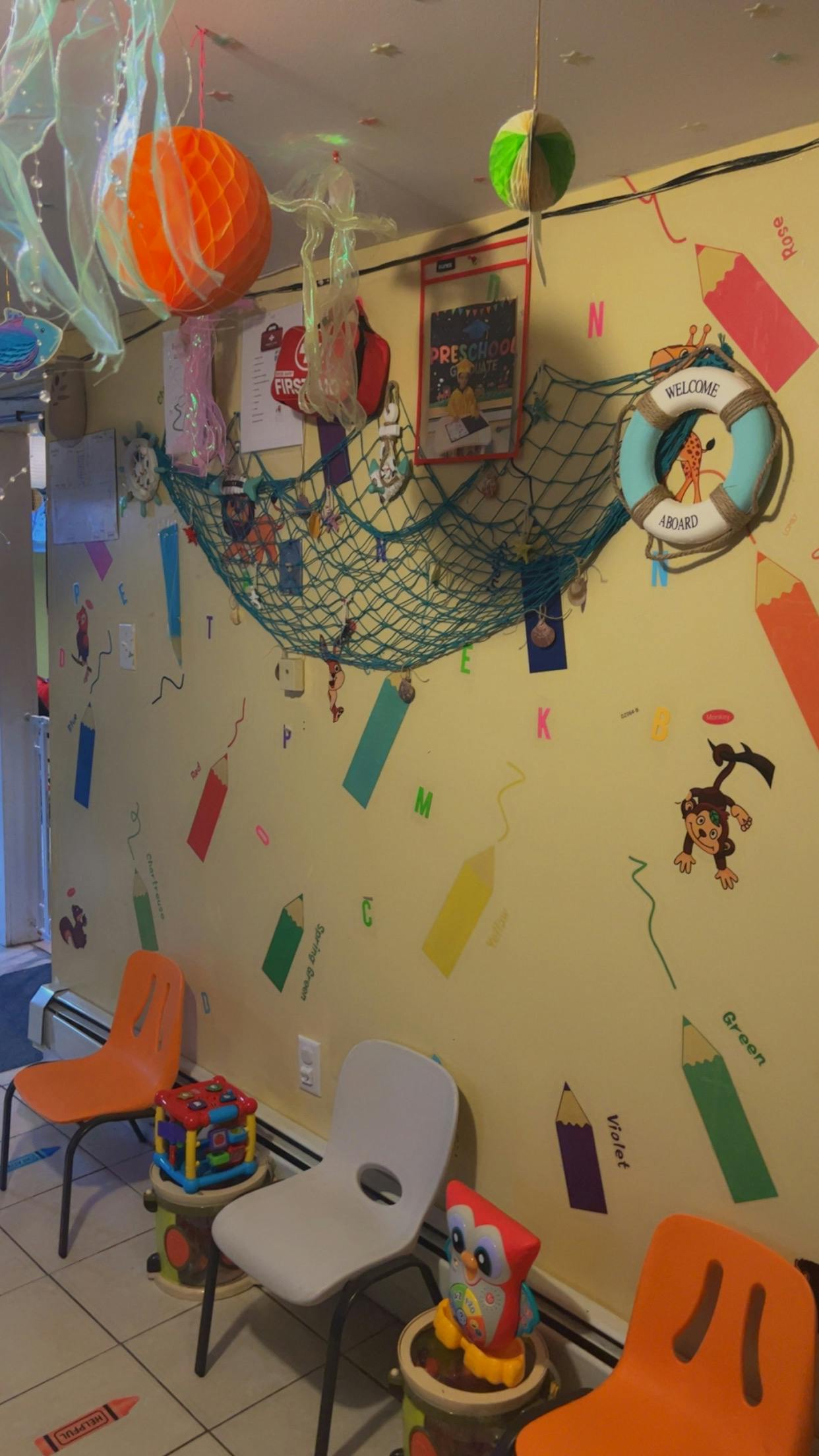 Wall decorated with crayon and letter cutouts, fishing net, and hanging decorations
