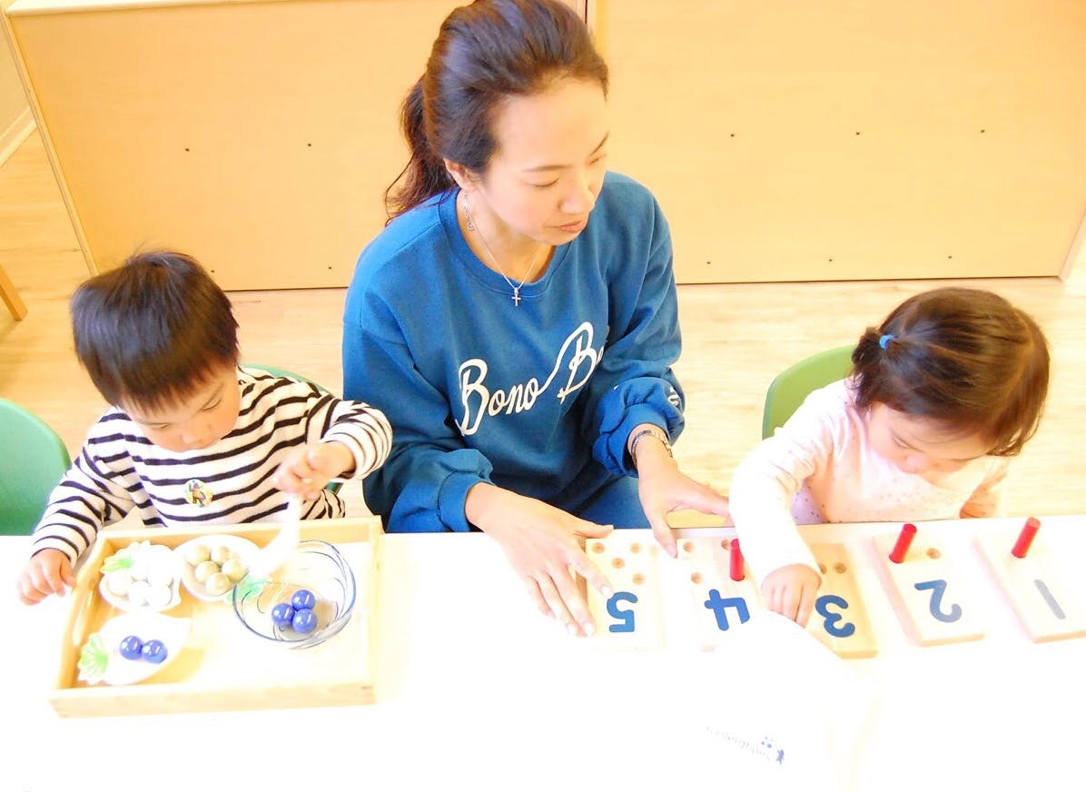 Adult and two children at a table with number learning toys
