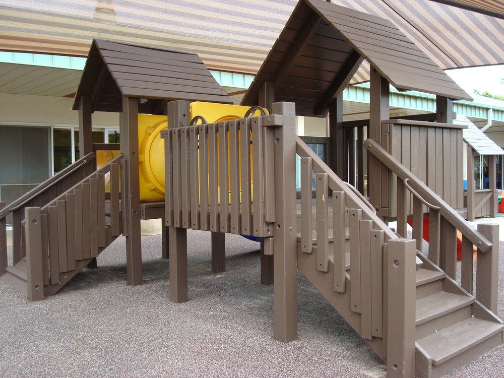 Brown wooden playground structure with stairs and yellow slide