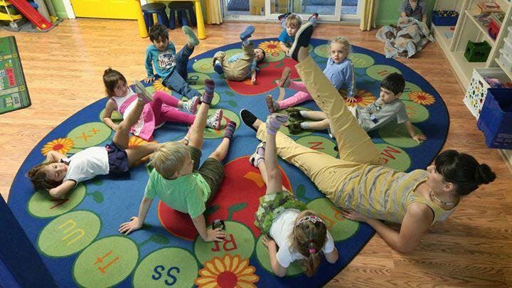 Adult and children lying on a colorful rug with legs in the air