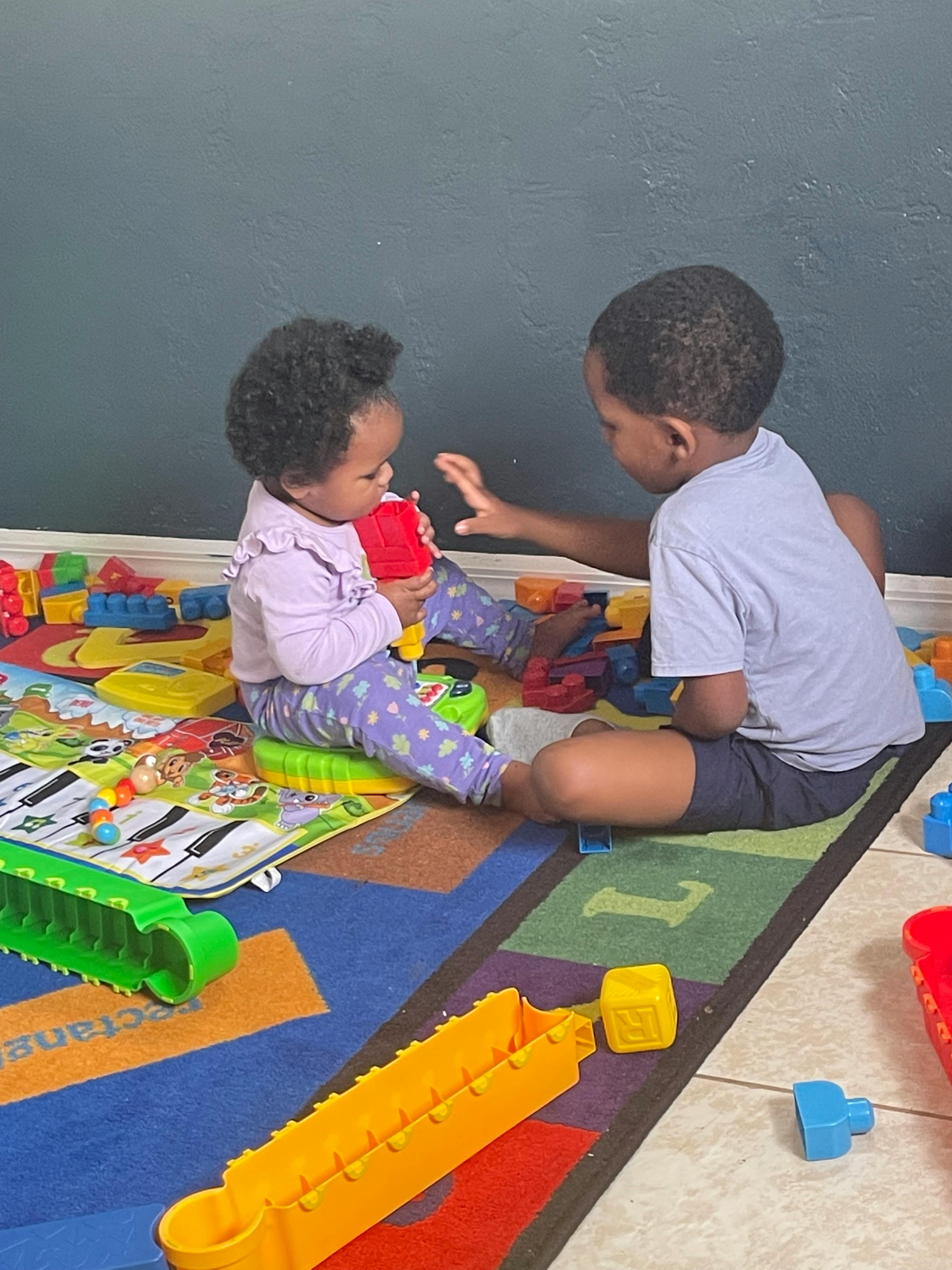 Two children playing with toys on a colorful rug