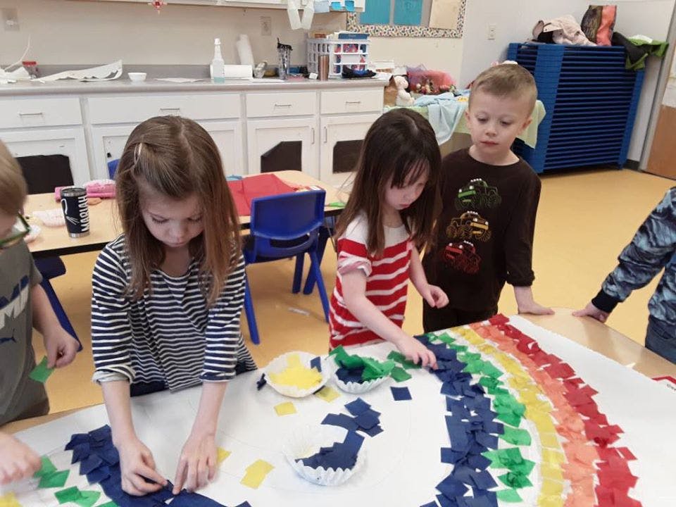 Children making a rainbow craft in a classroom