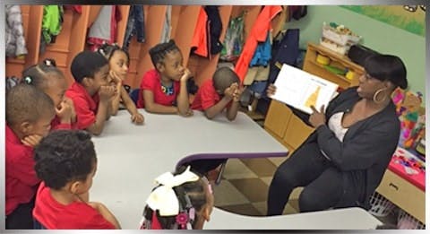Person reading a book to children in a classroom