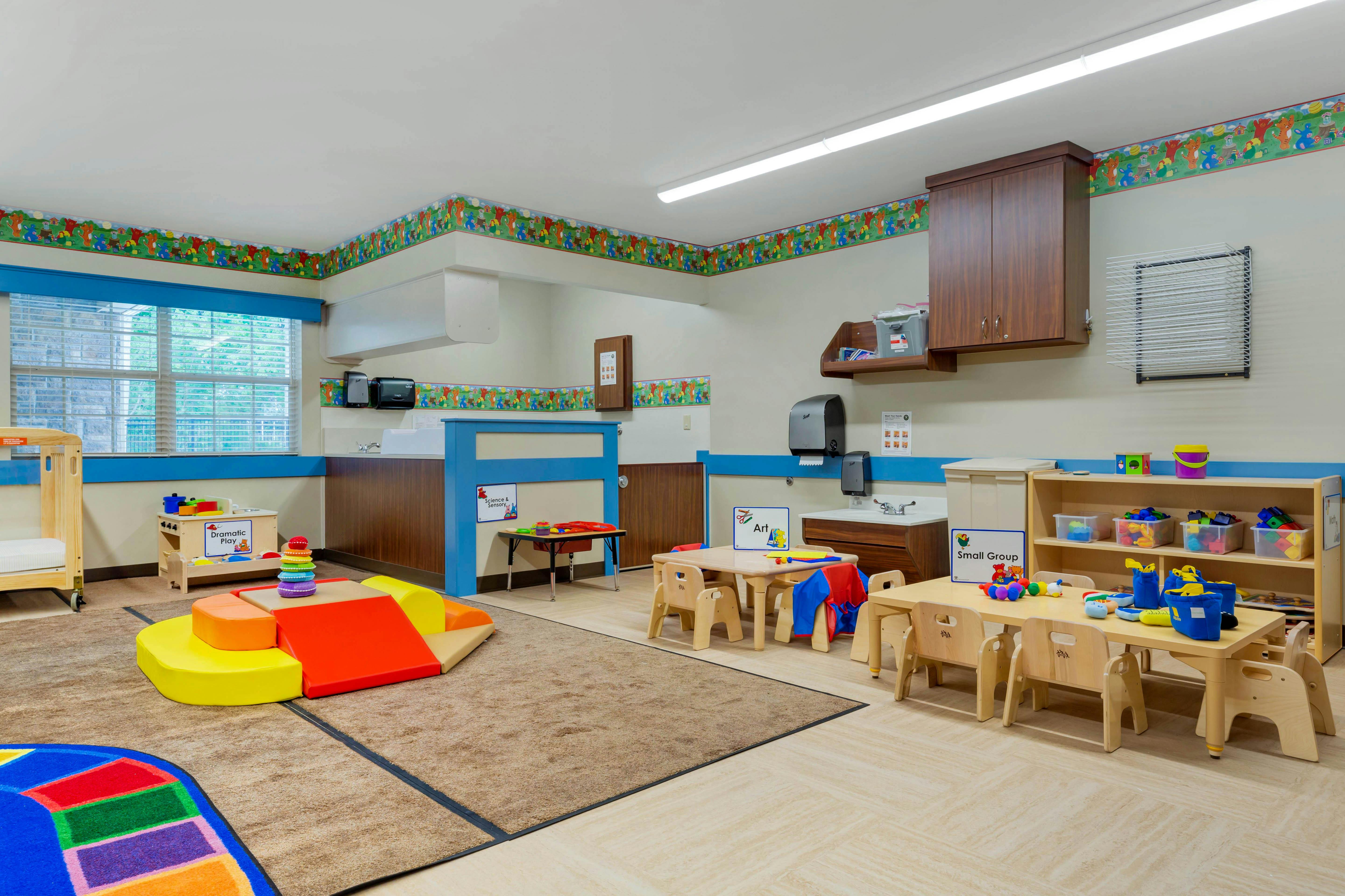 Classroom with children's furniture, play kitchen, soft play area, and activity tables