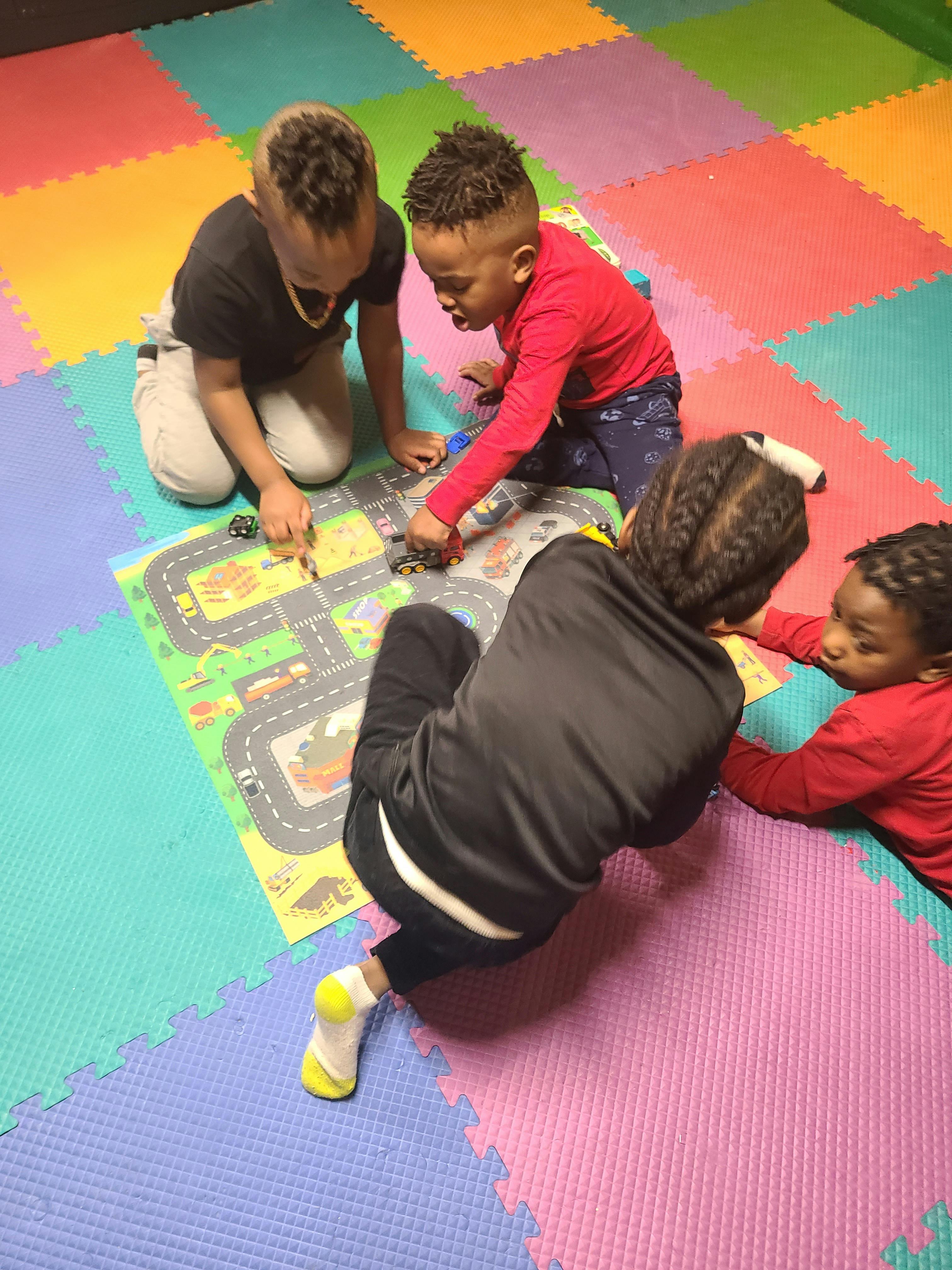 Four children playing with toy cars on a road map mat