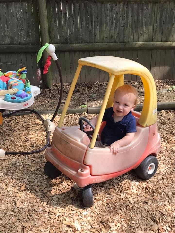 Child in a toy car on wood chips
