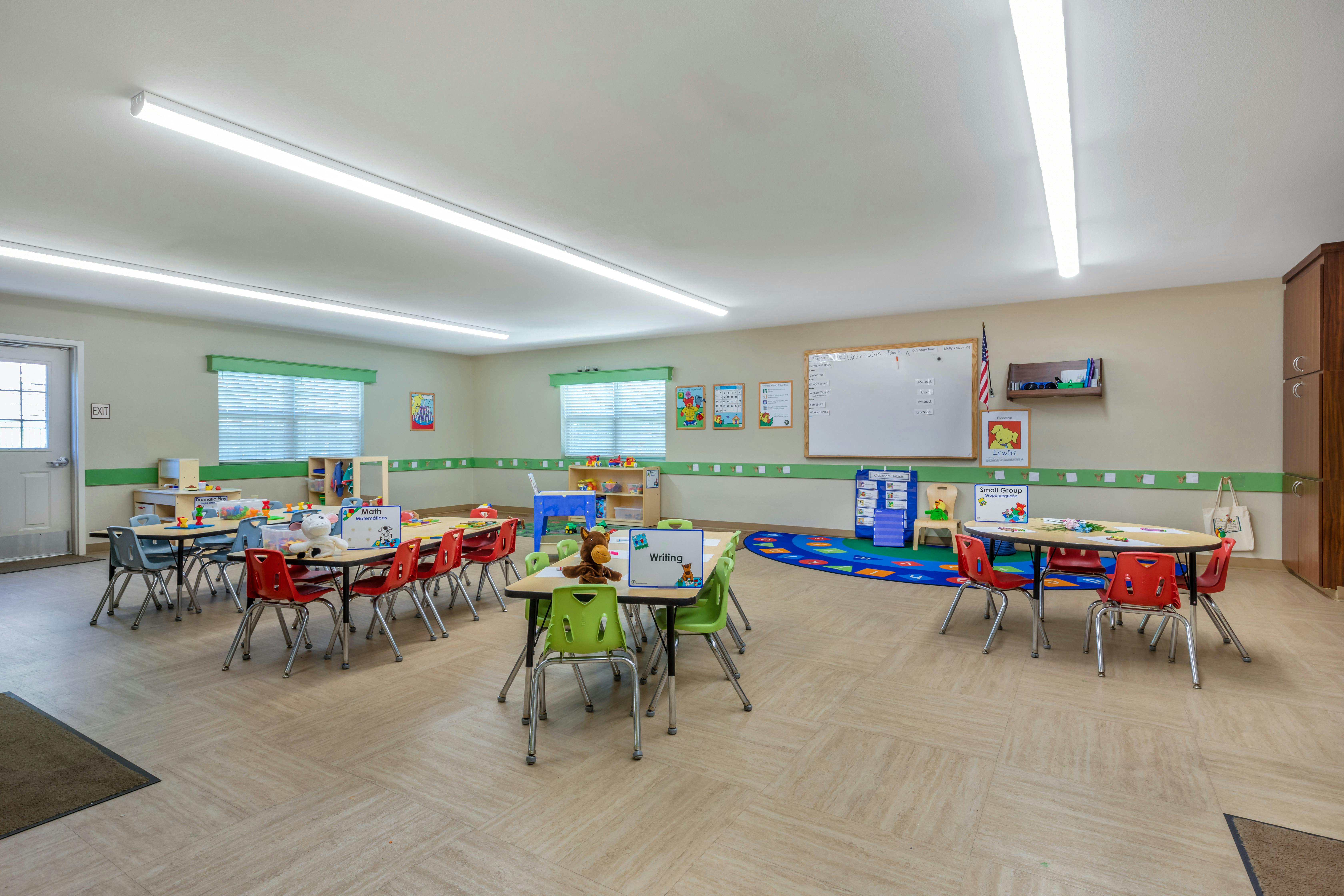 Classroom with multiple tables and chairs, whiteboard, and learning materials