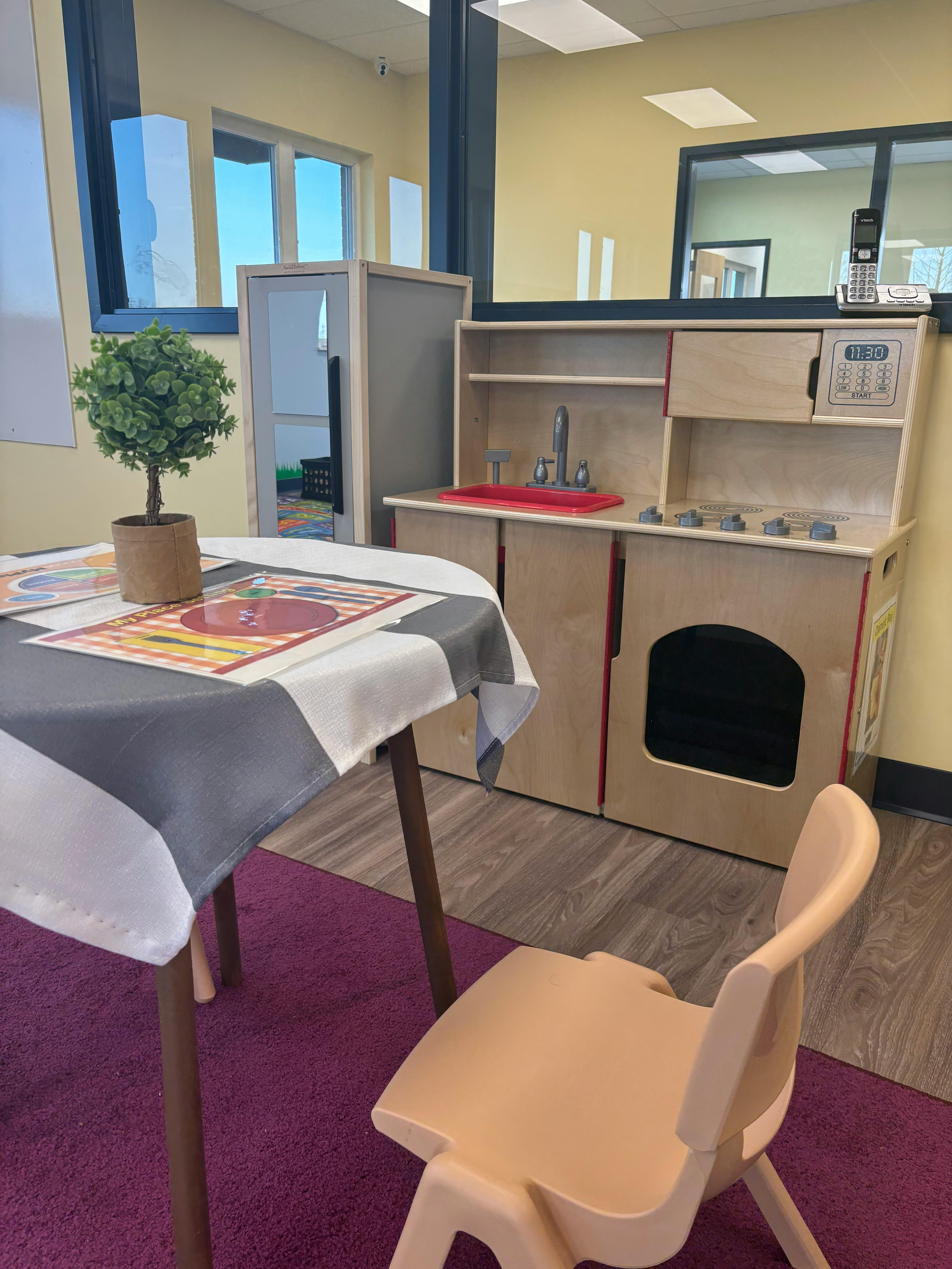 Play kitchen set with a small table and chair in a room