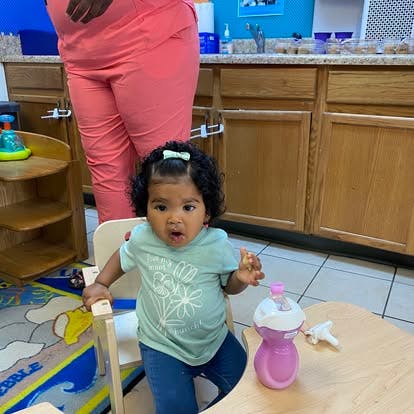 Child sitting in a high chair with a water bottle on a table