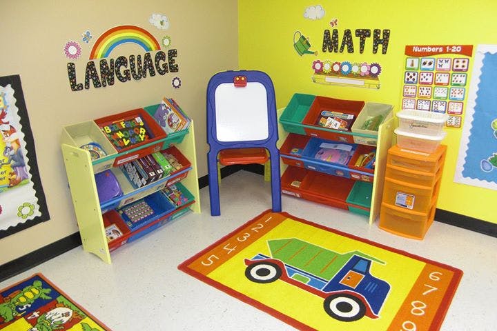 Classroom with toy storage, easel, and rugs with truck and turtle designs