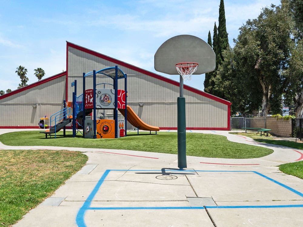 Basketball hoop on a court next to a playground structure