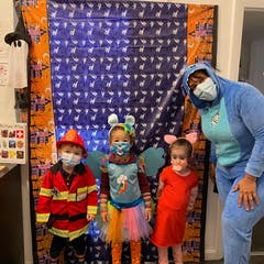 Three children and one adult in costumes and face masks