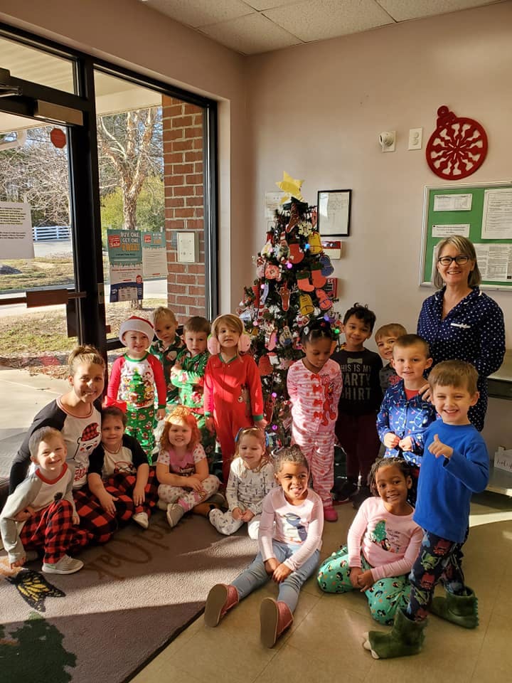 Adult and children in pajamas posing in front of a decorated Christmas tree