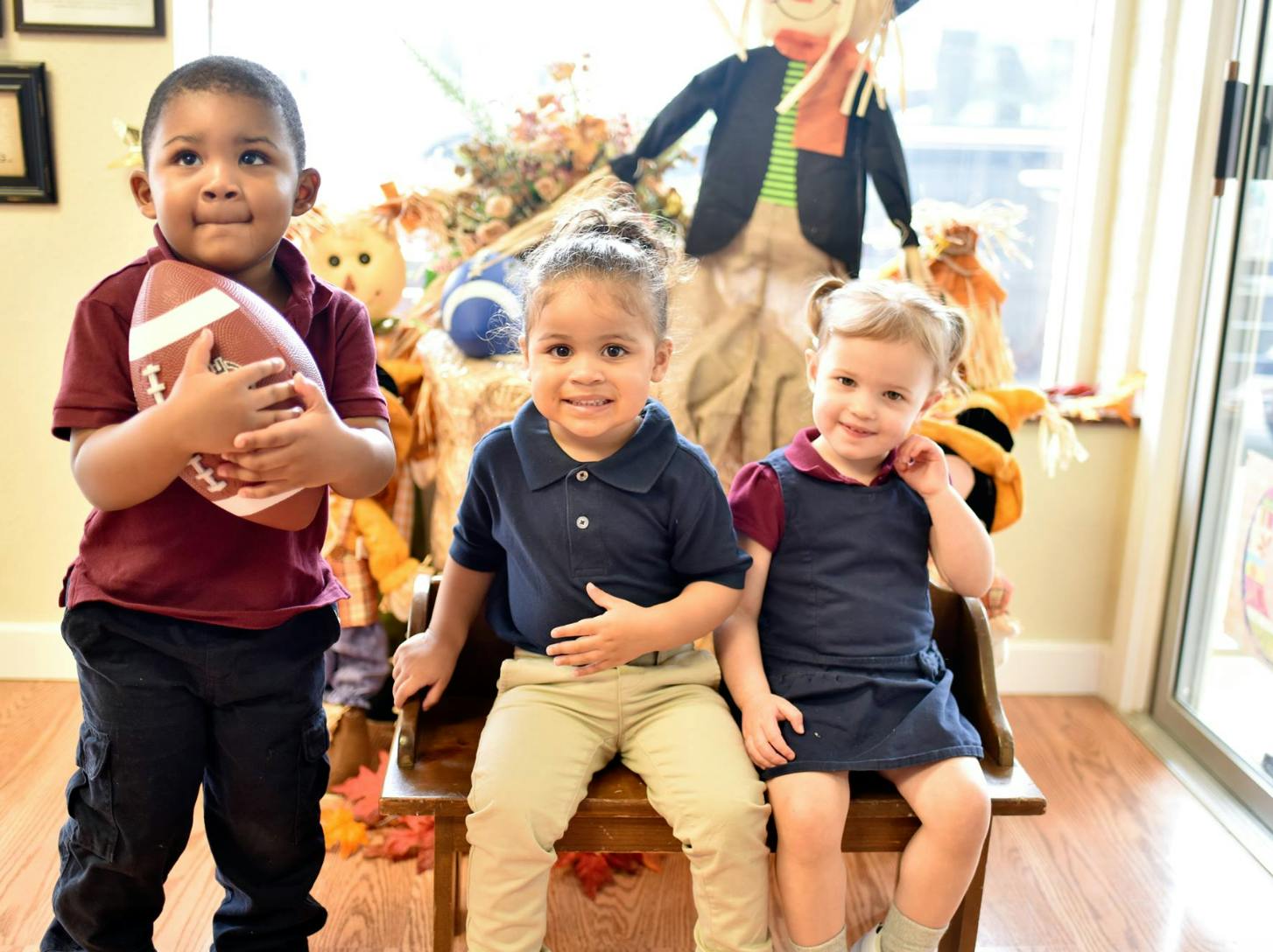 Three children posing, one holding a football