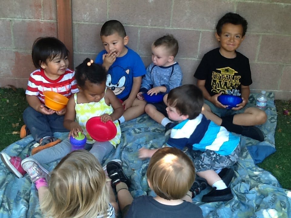 Group of children sitting on a blanket with bowls