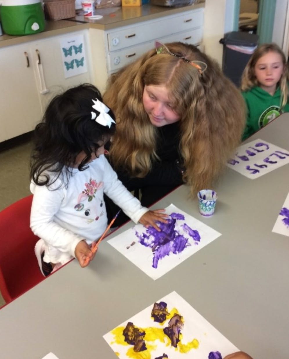 Person and child finger painting at a table