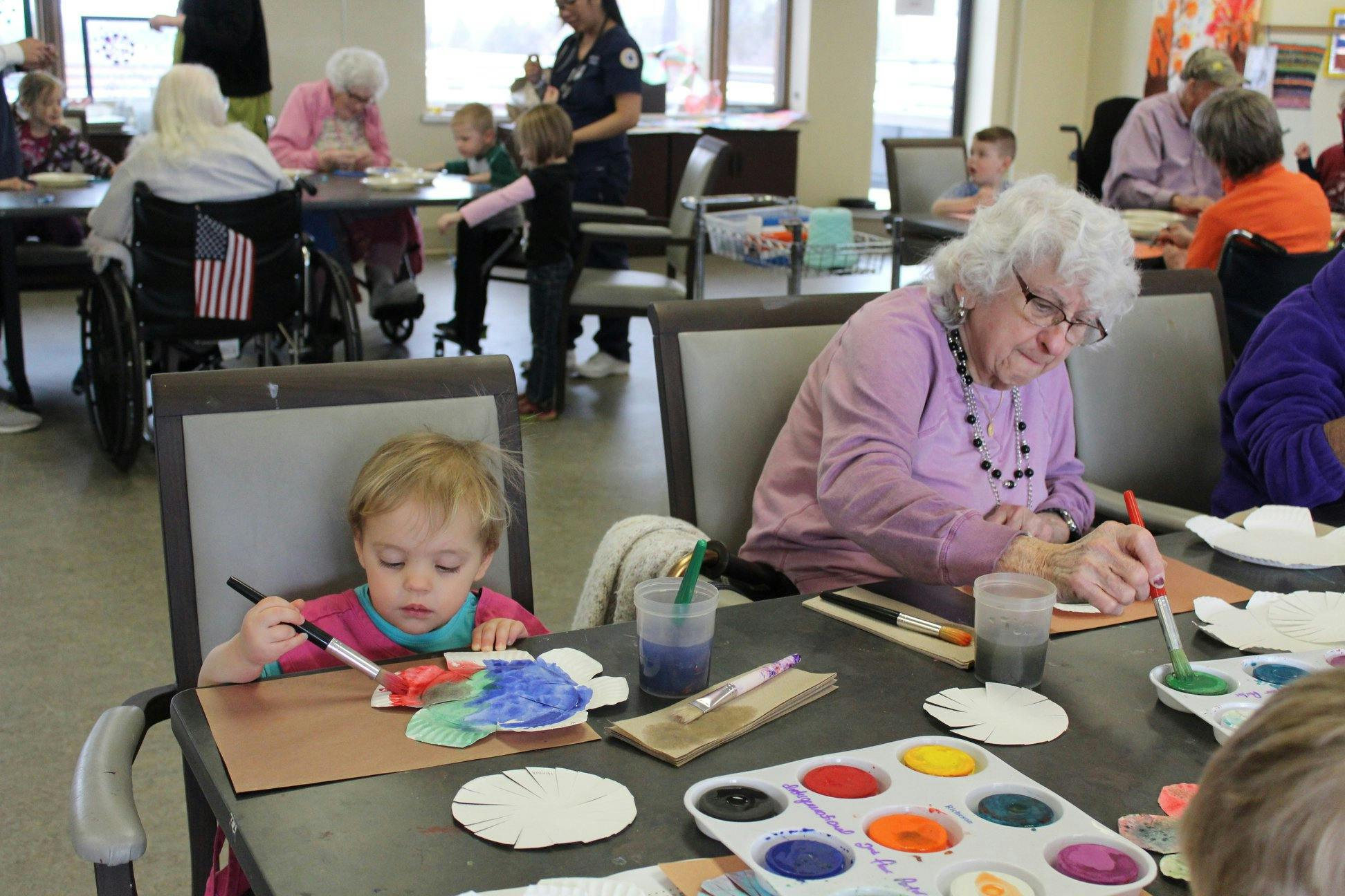 Child and older person painting at a table