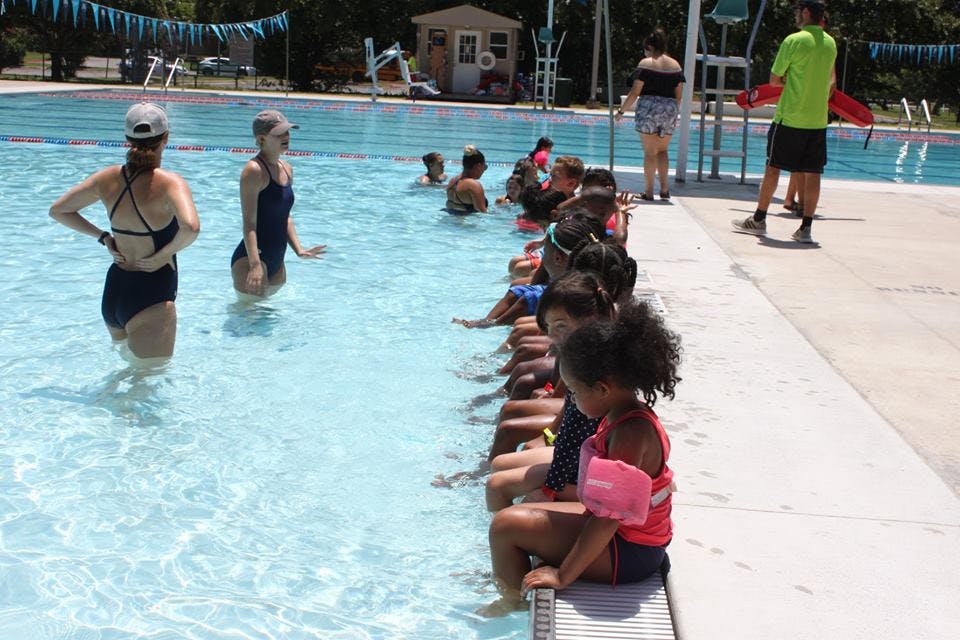 People in a swimming pool with children sitting on the edge