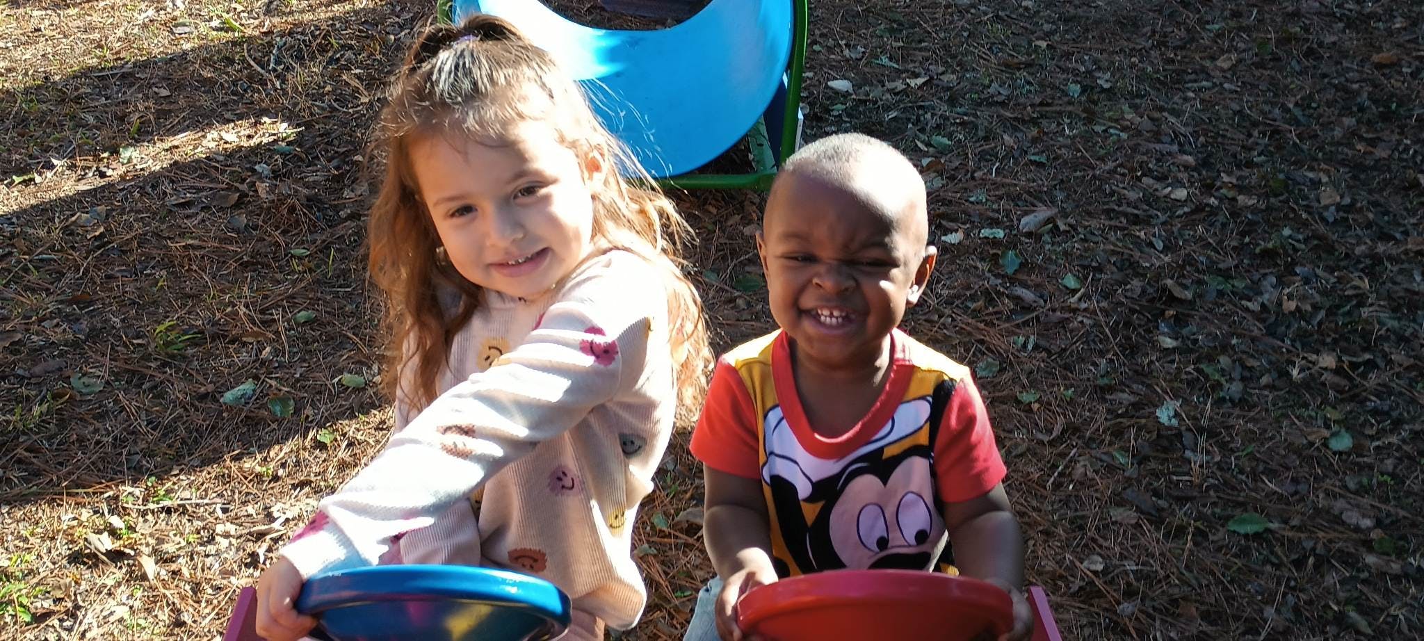Two children playing with buckets outdoors