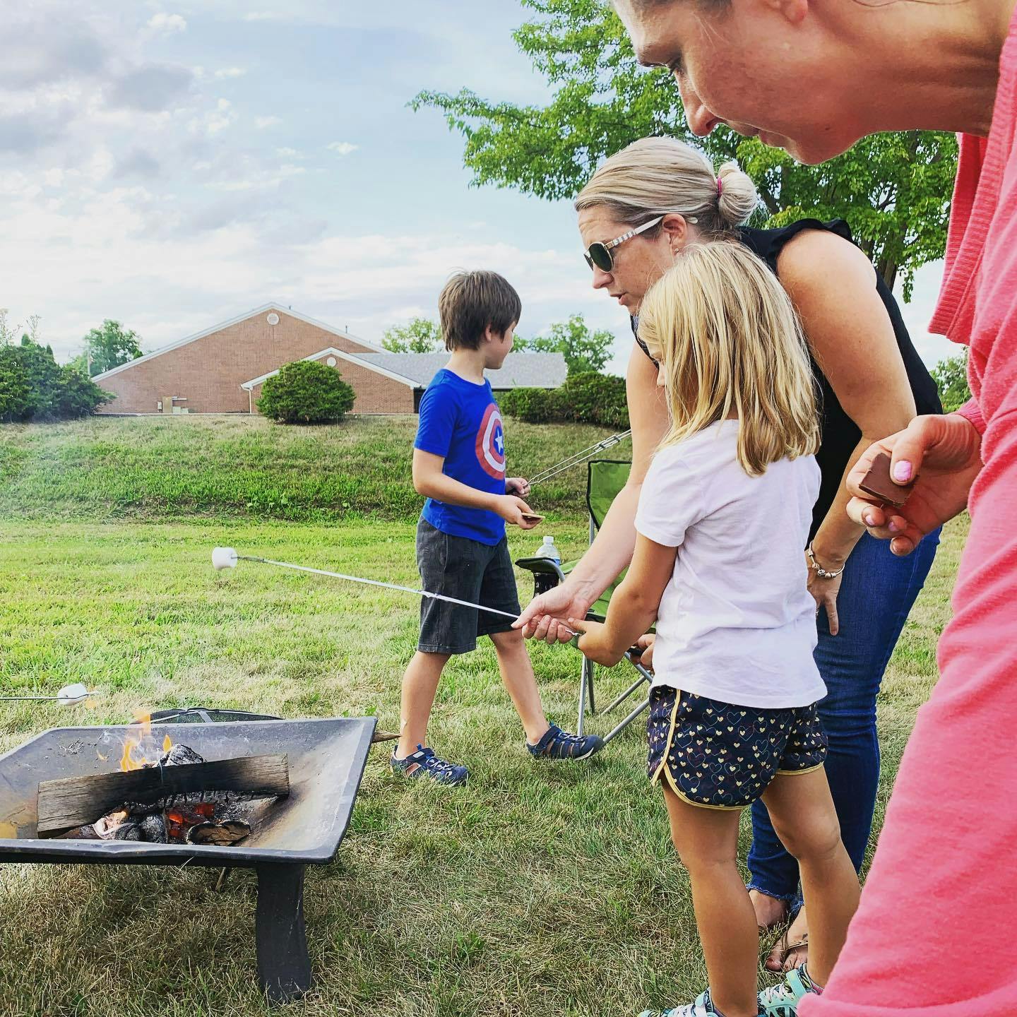 Adult and two children roasting marshmallows over a fire pit