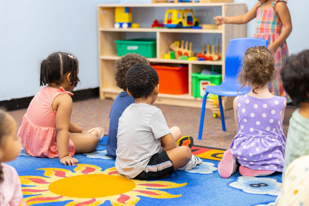 Children sitting on a rug in a classroom
