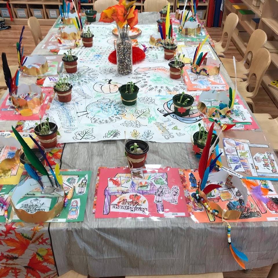 Table set with small potted plants, colorful drawings, and craft supplies
