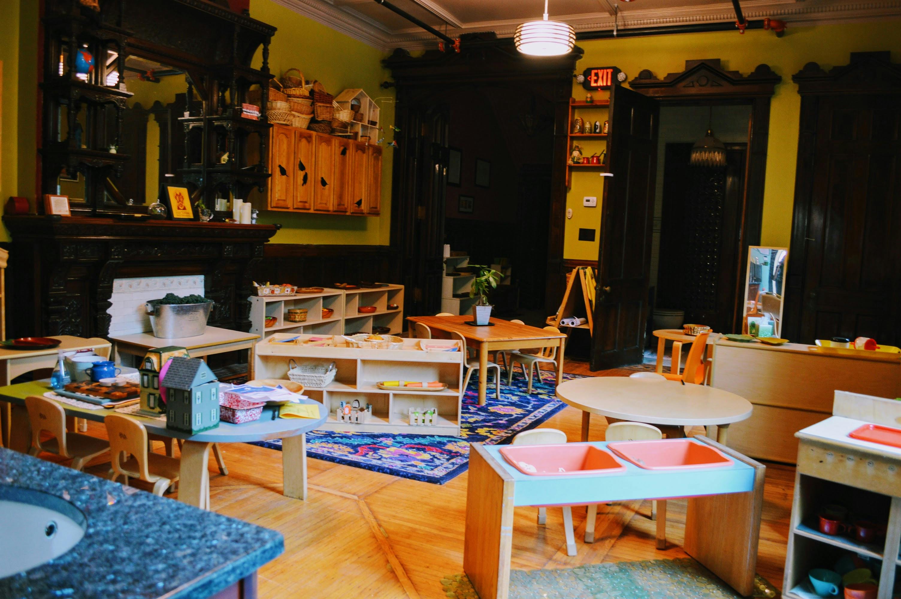 Classroom with small tables, chairs, and shelves with learning materials