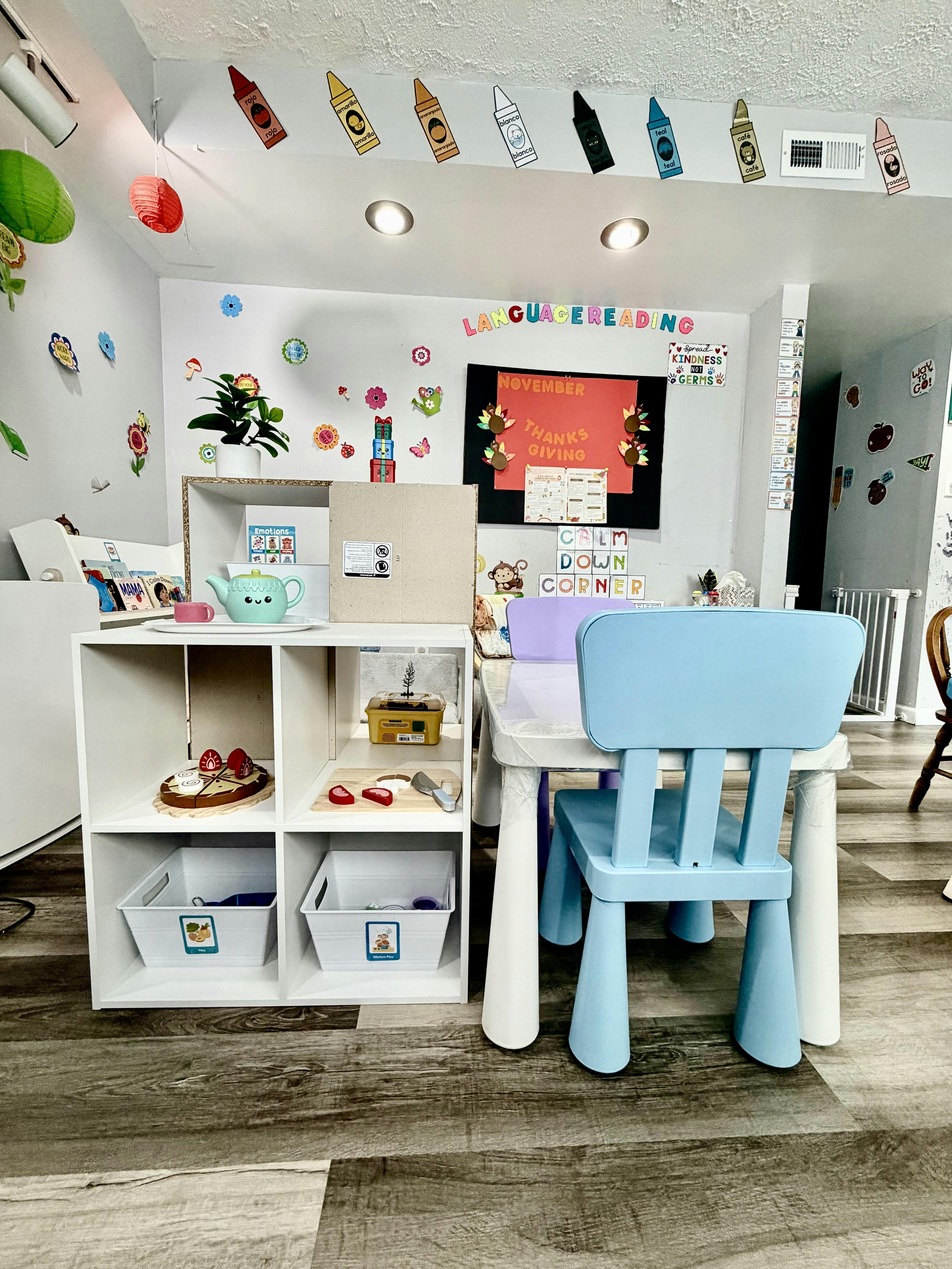 A colorful classroom with children's furniture, shelves with toys, and educational wall decorations