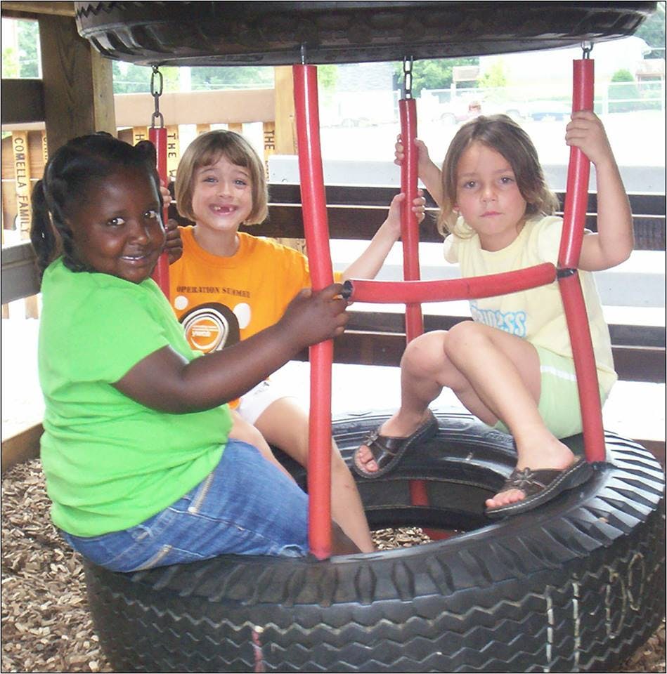 Three children sitting in a tire swing