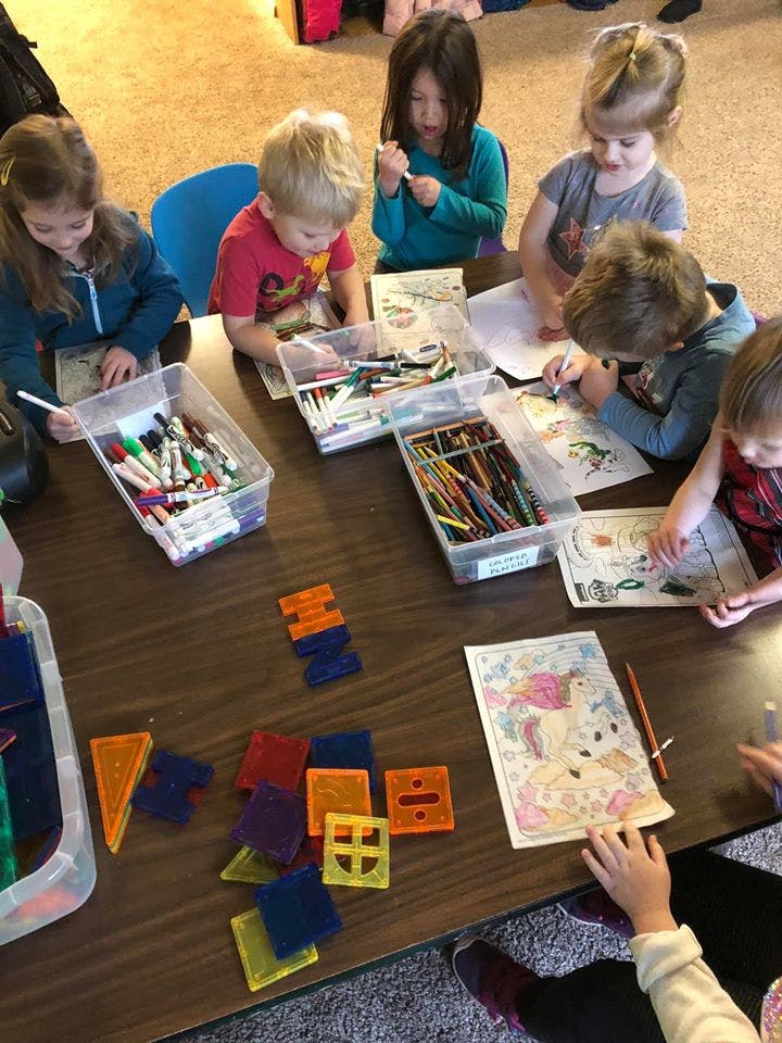 Children coloring and playing with magnetic tiles at a table