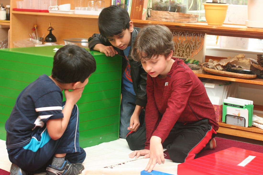 Three children looking at something on the floor