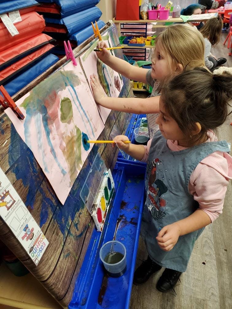 Two children painting at an easel in a classroom