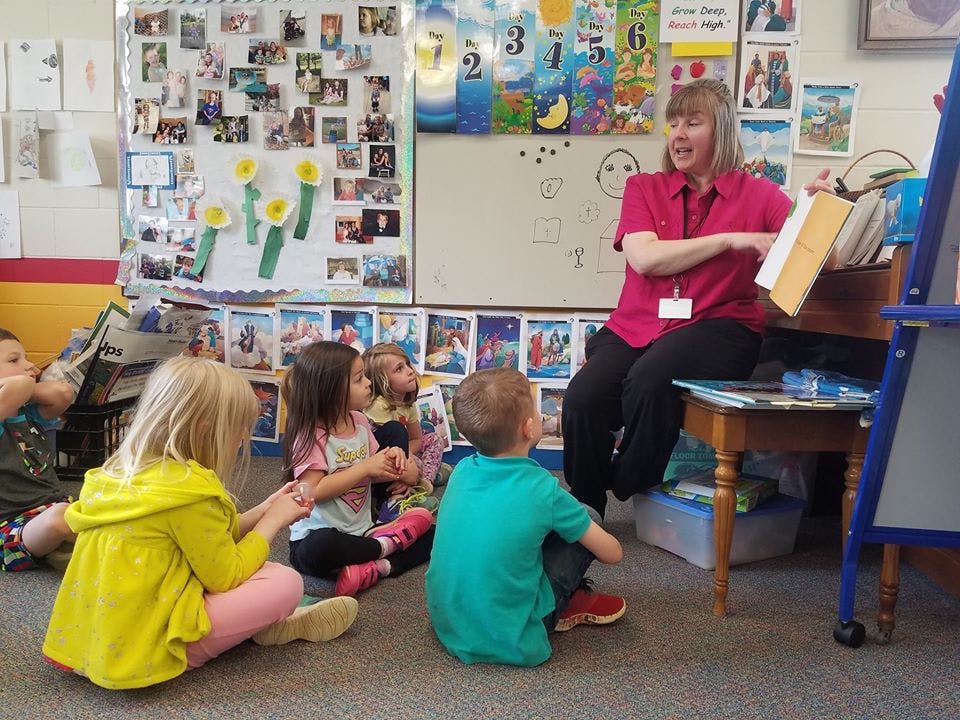 Person reading a book to children in a classroom