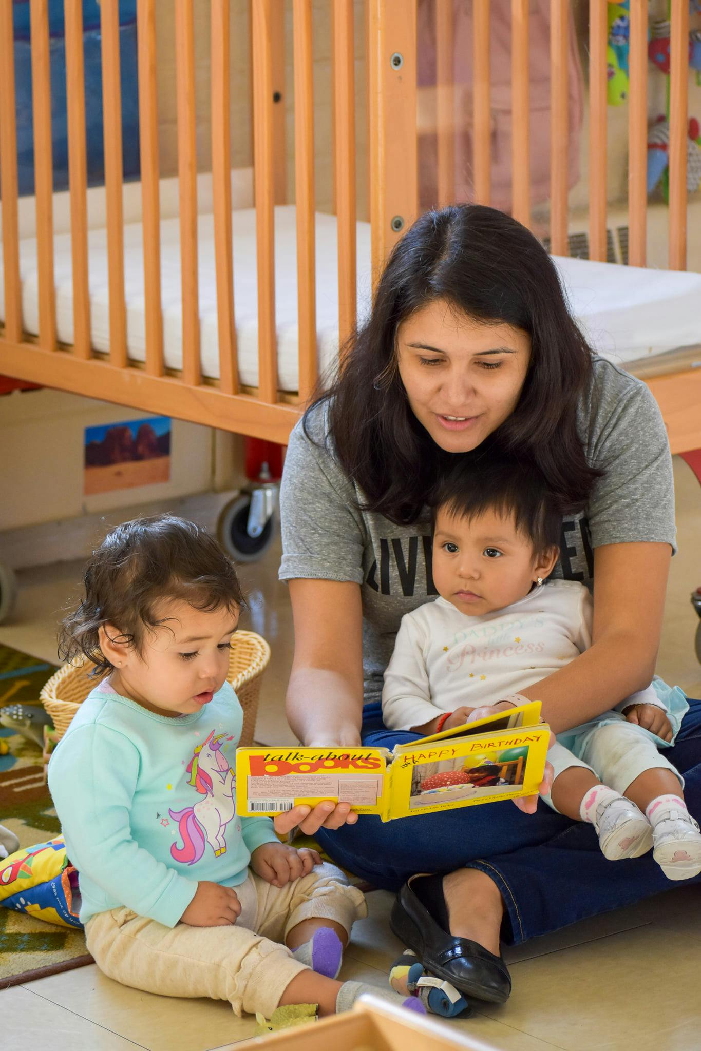 Person reading a book to two children