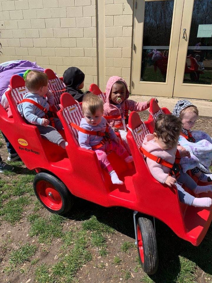 Multiple children in a red multi-seat stroller