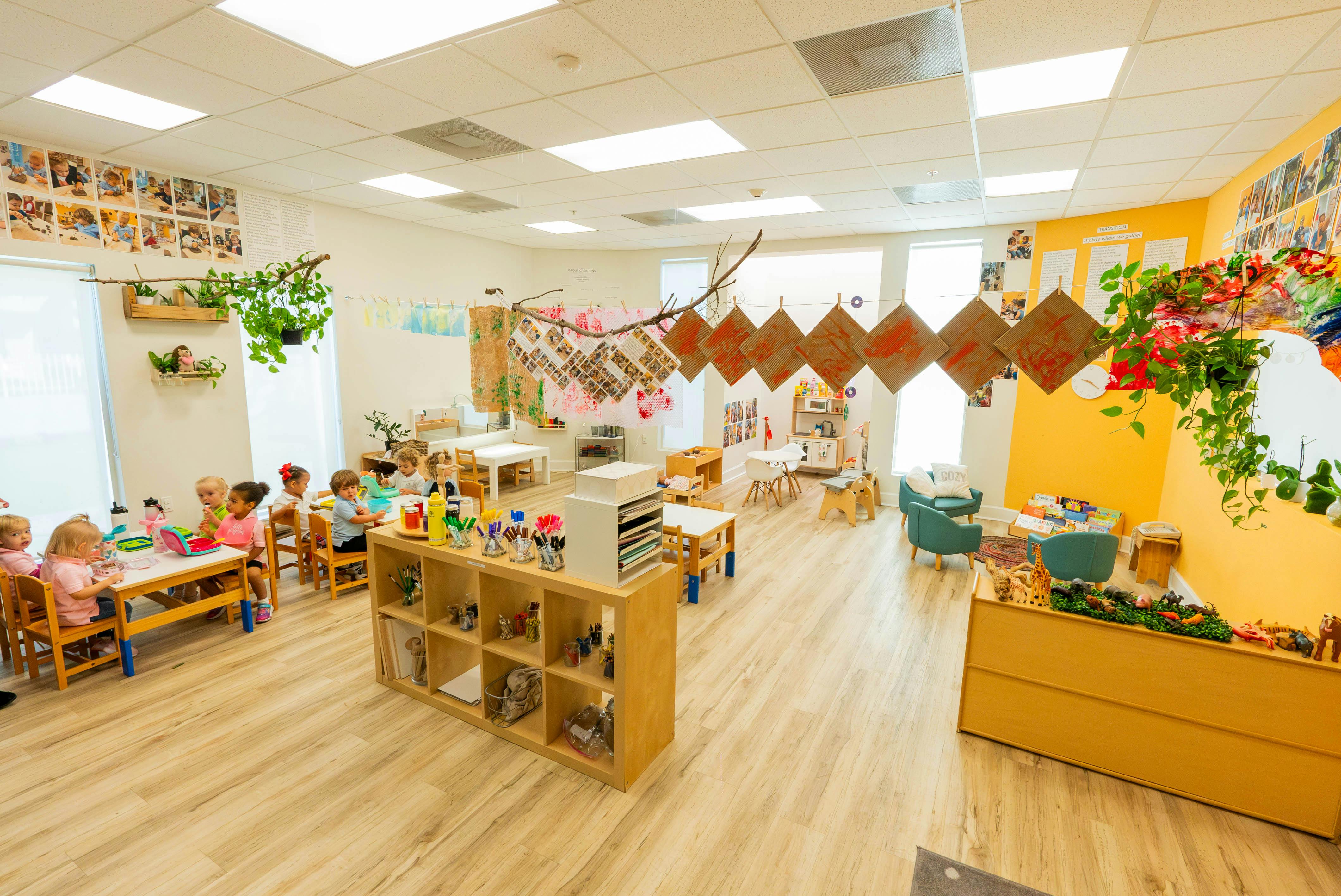 Children eating and playing in a brightly lit classroom with decorations