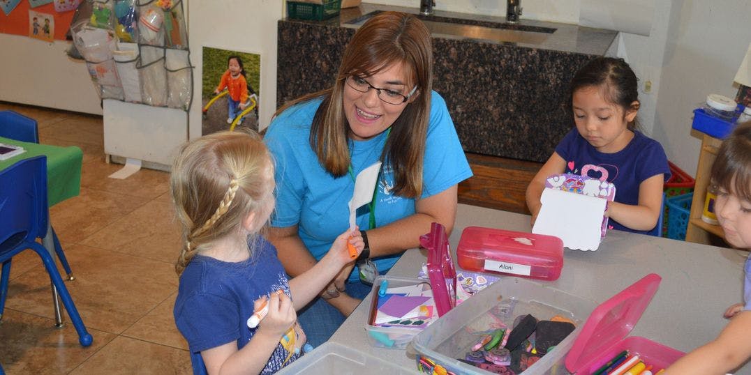 Person and two children at a table with craft supplies