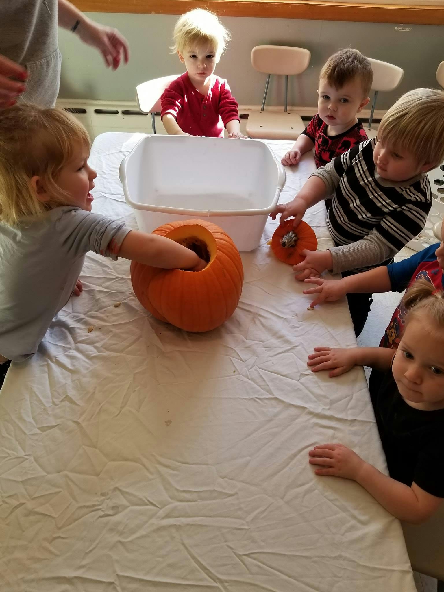 Children on a table with pumpkins and a white tub