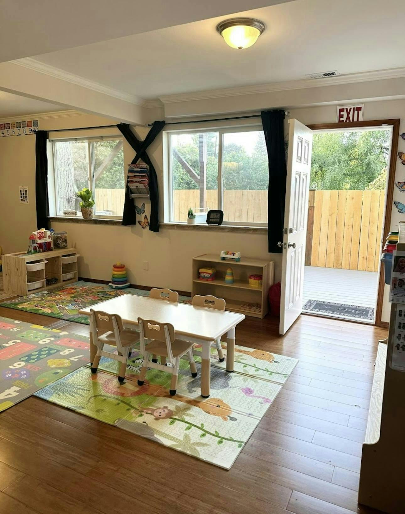 Classroom with small table and chairs, colorful rugs, and an open door