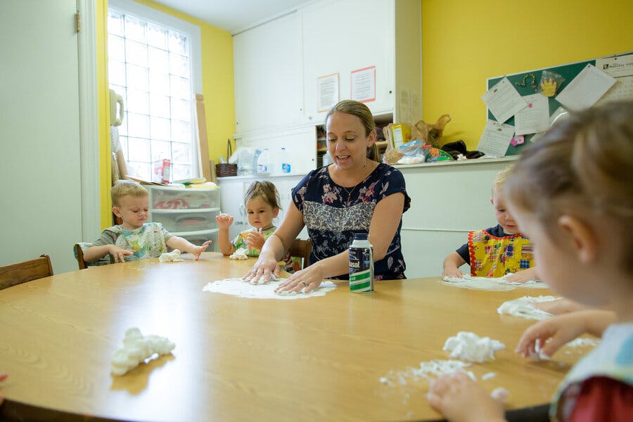 Adult and children at a table playing with white dough