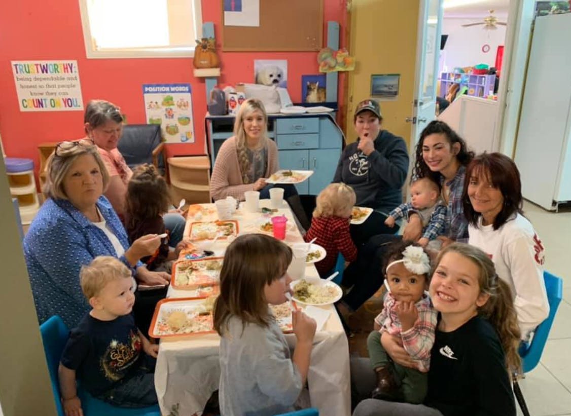 People and children gathered around a table with food