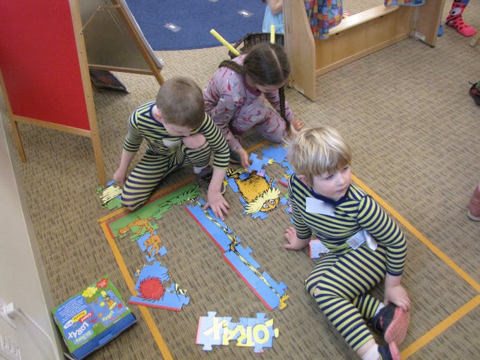 Three children playing with a floor puzzle