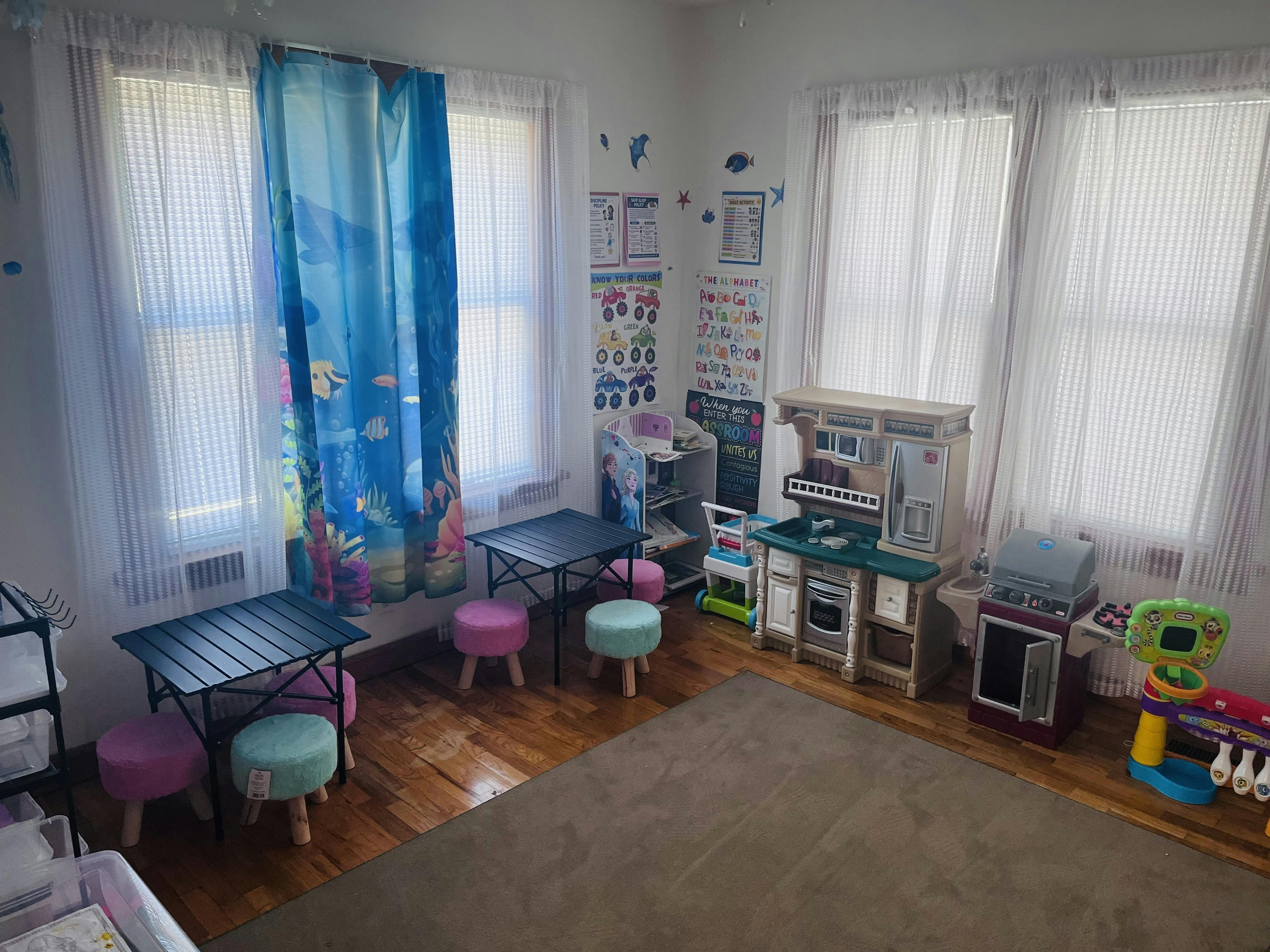 Playroom with child-sized tables, chairs, and a toy kitchen