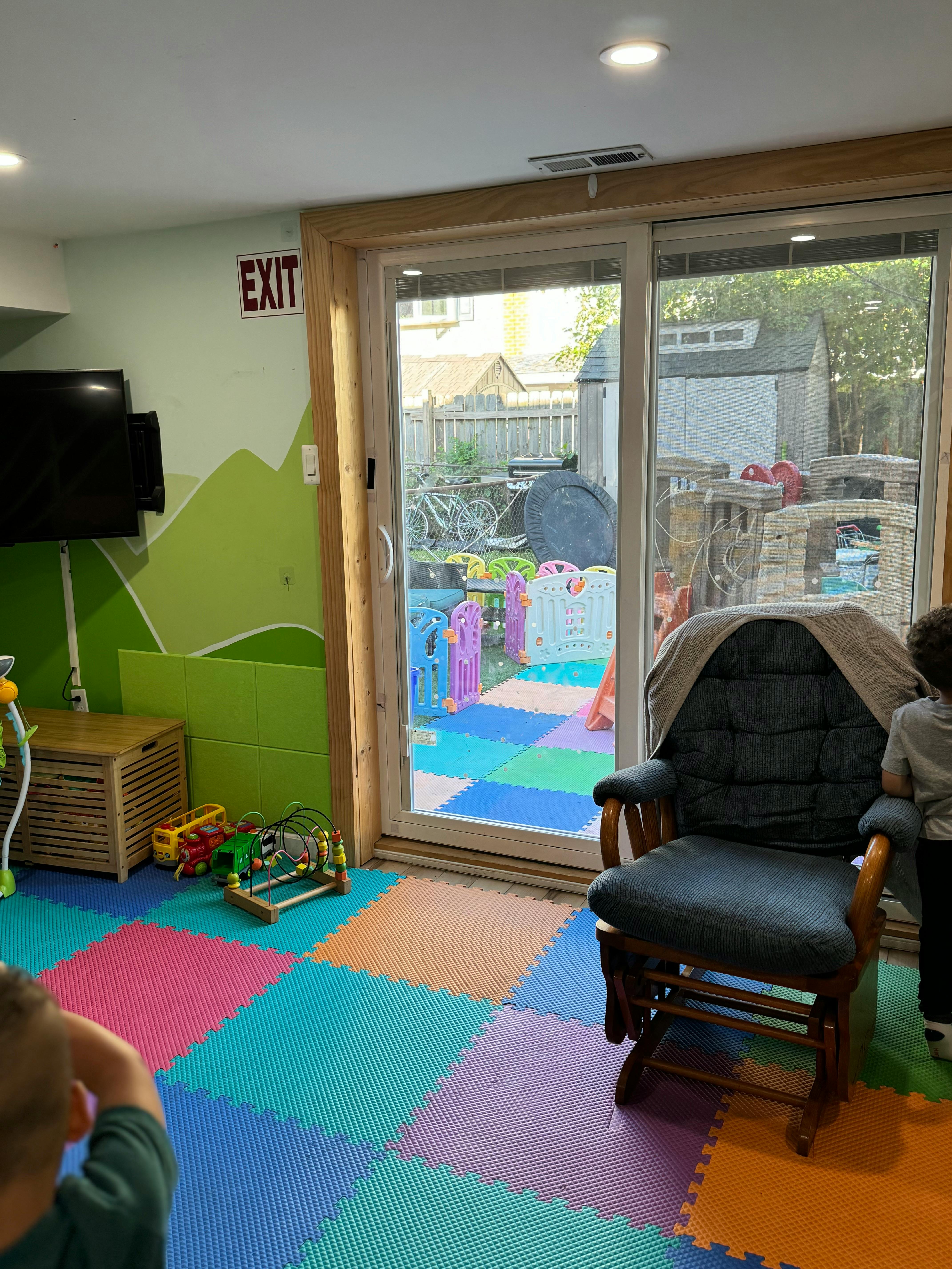 Playroom with colorful floor mats and a sliding glass door to a backyard