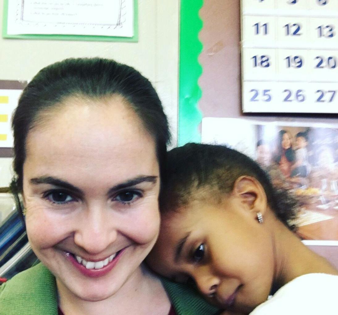 Person smiling with a child resting head on their shoulder